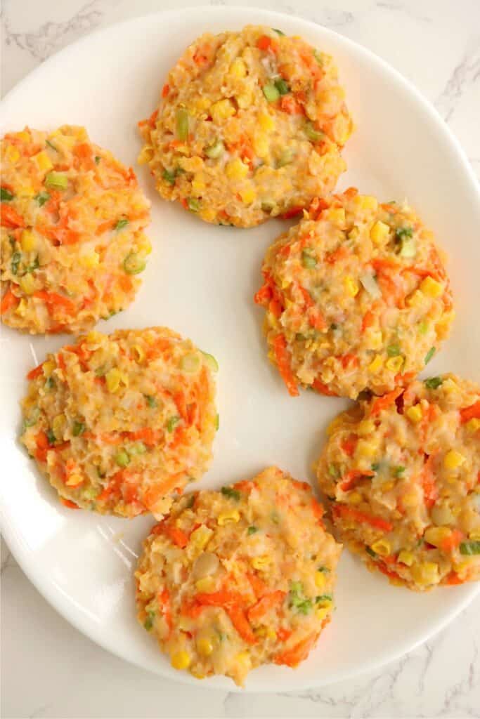 Overhead shot of mashed potato and vegetable patties with no coating on plate.