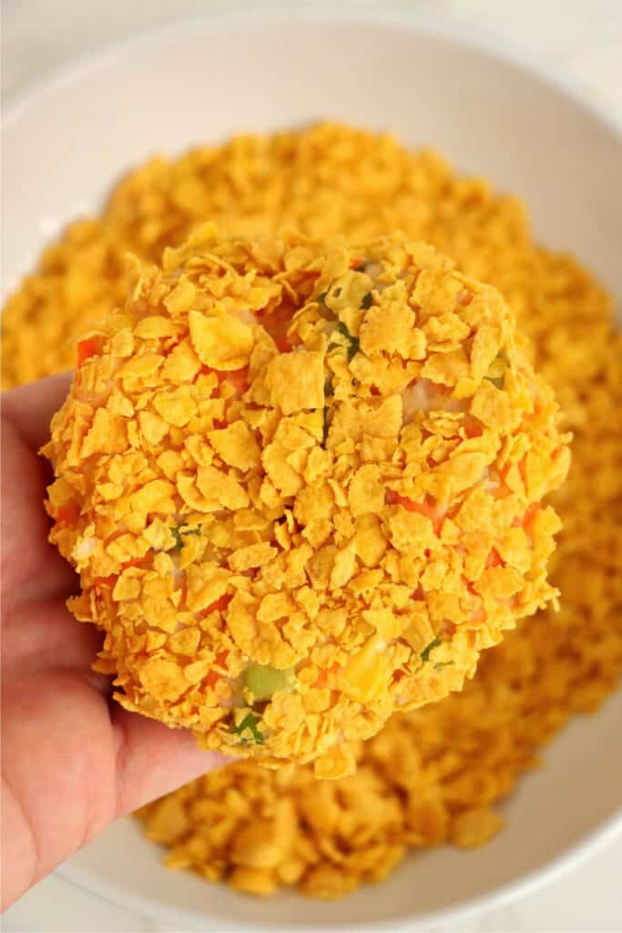 Closeup shot of hand holding an uncooked mashed potato pattie coated with cornflakes.