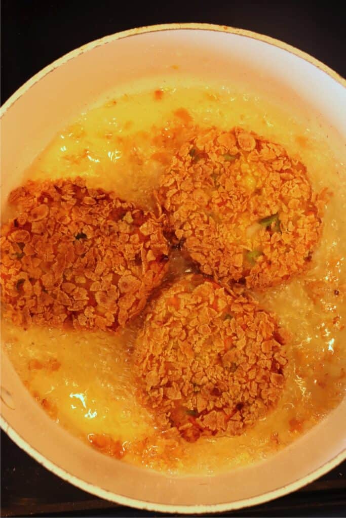 Overhead shot of mashed potato and vegetable patties frying in pan. 