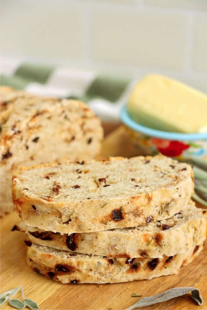 Closeup shot of three slices of sage bread stacked atop one another with more sage bread in background