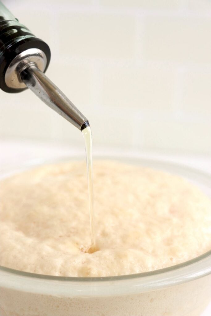 Closeup shot of olive oil being poured into yeast mixture.