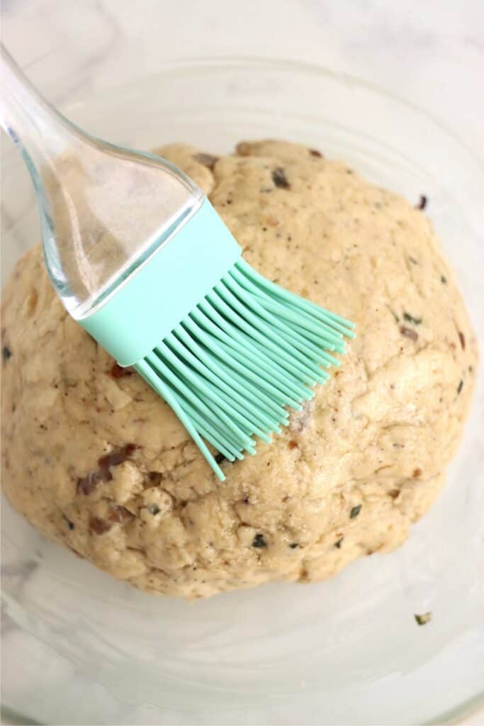 Overhead shot of oil being brushed on dough ball