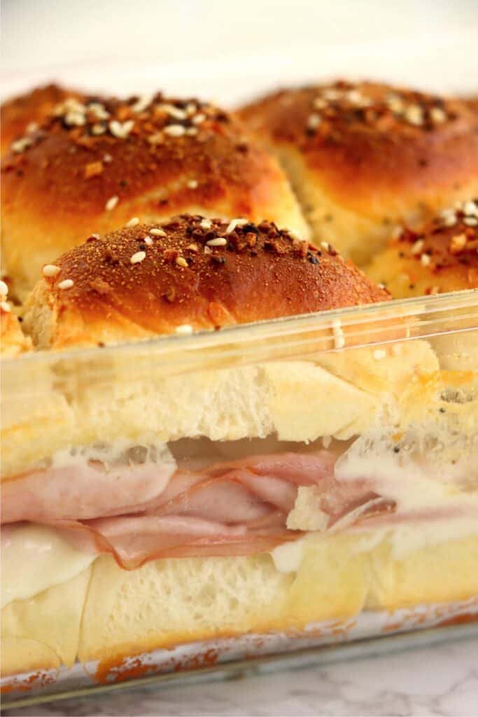 Closeup shot of baked turkey and cheese sliders in baking dish. 