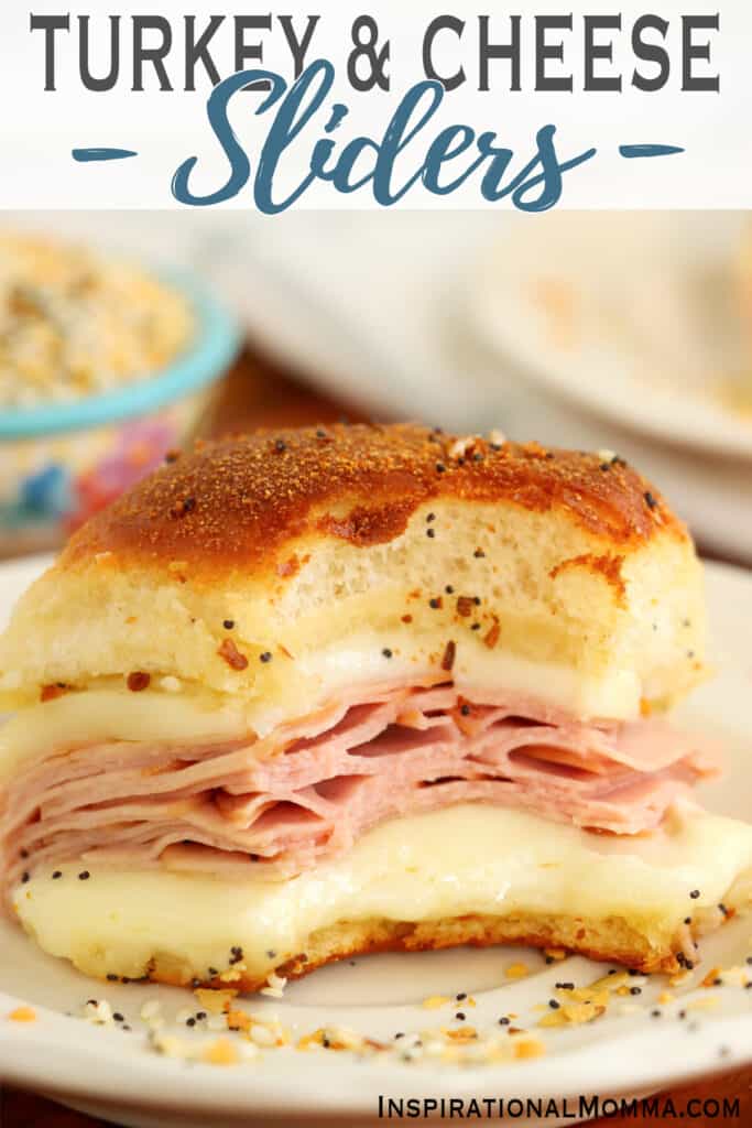 Closeup shot of baked turkey and cheese slider with bite taken out on plate.