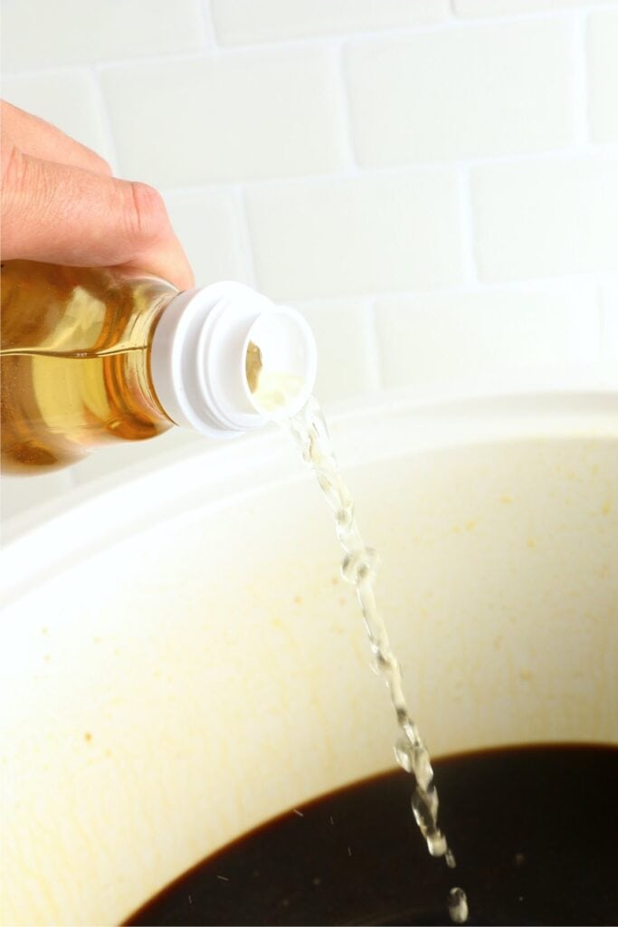 Rice vinegar being poured into slow cooker. 