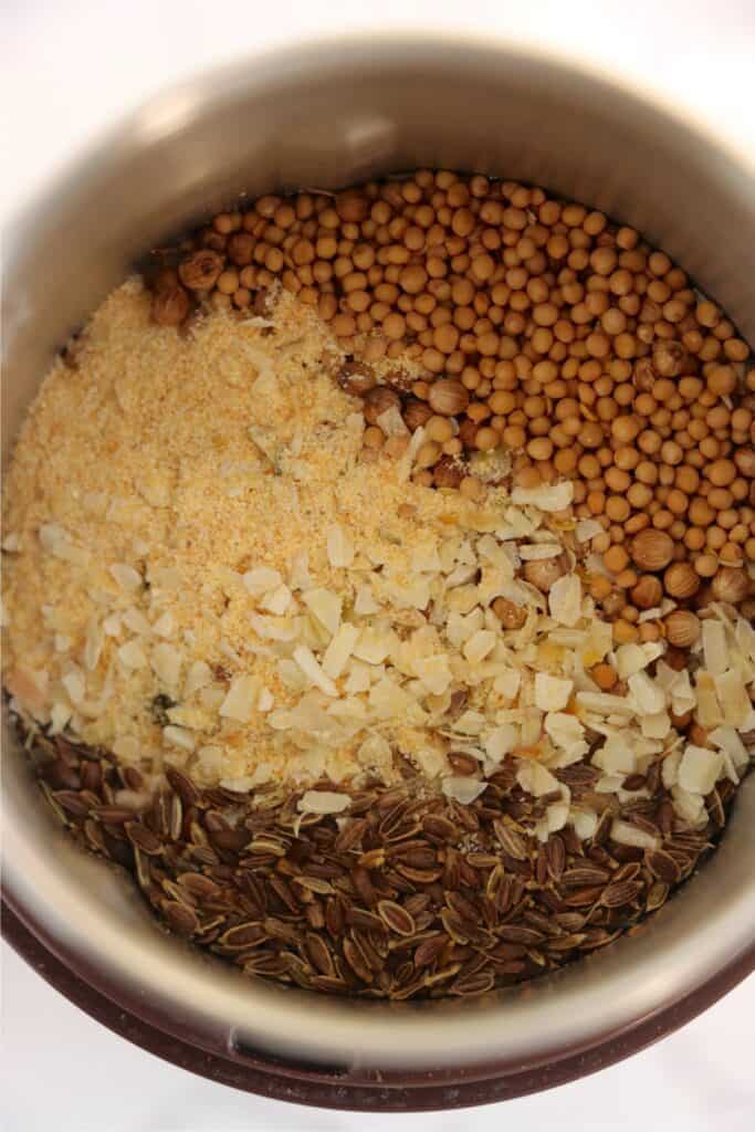 Overhead closeup shot of dill pickle seasoning ingredients in spice grinder. 