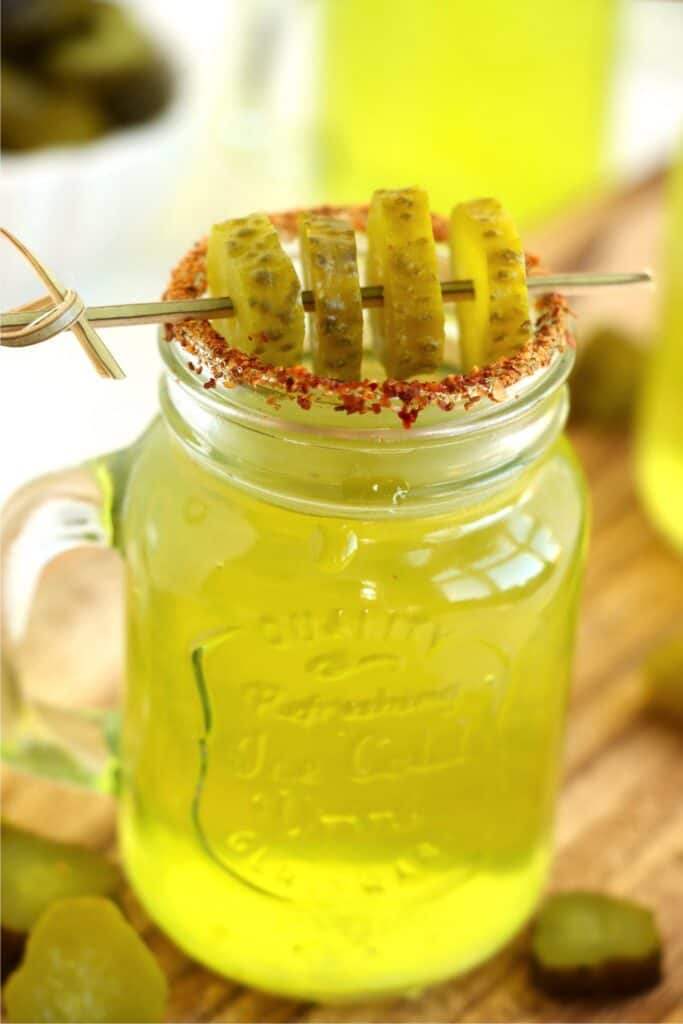 Closeup shot of pickle shot garnished with Tajin and dill pickle slices.