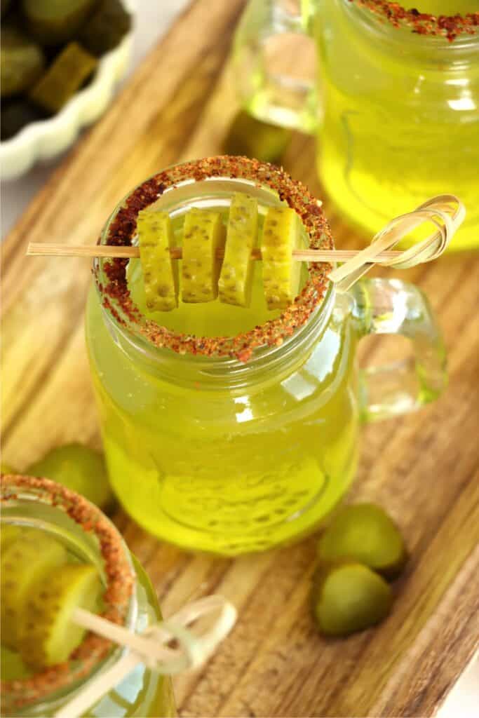 Overhread shot of vodka pickle shot in shot glass garnished with dill pickles.