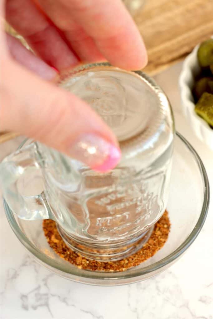 Closeup shot of shot glass being dipped in Tajin.