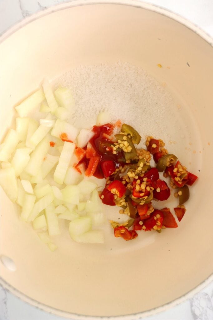 Closeup shot of salt, onions, and peppers in a skillet.