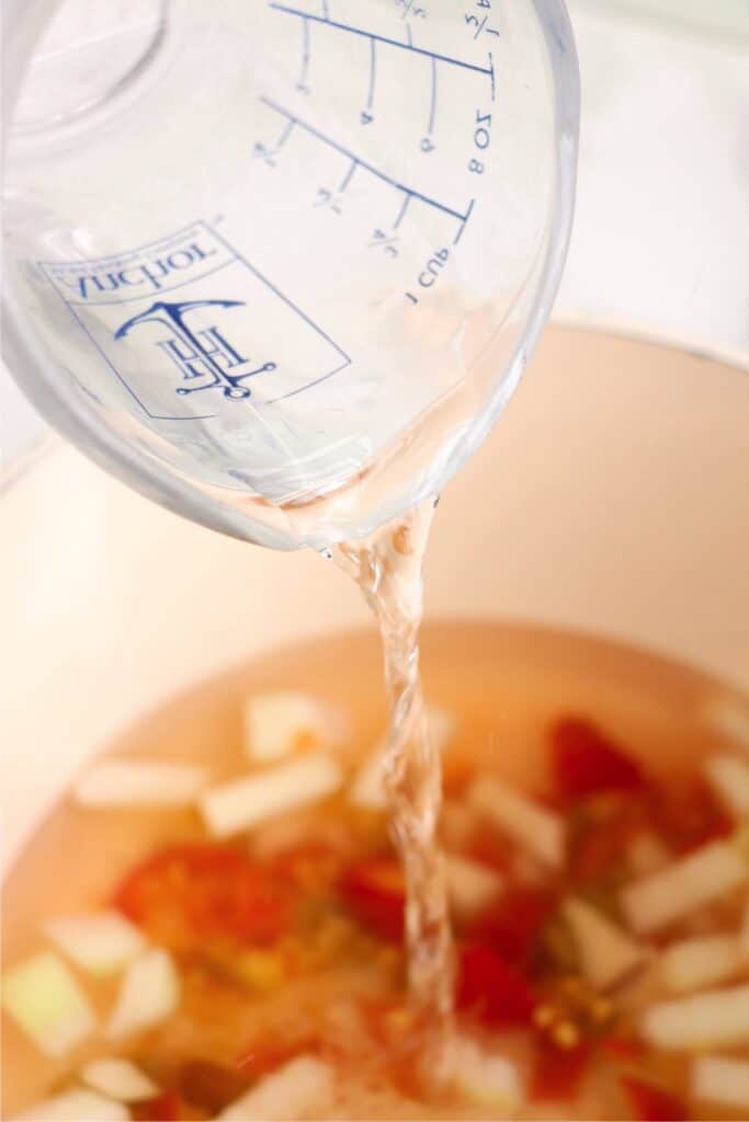 Water being poured into skillet with pickling ingredients. 