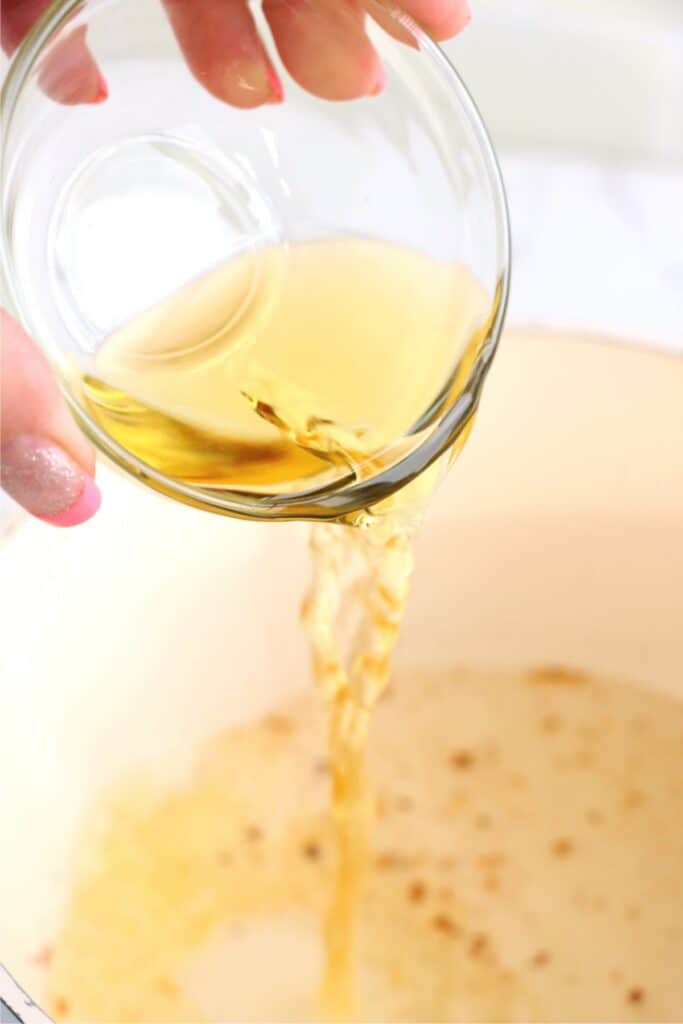 Closeup shot of apple cider vinegar being poured into pot. 