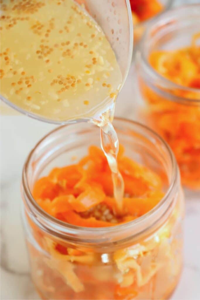 Pickling juice being poured over habanero peppers. 