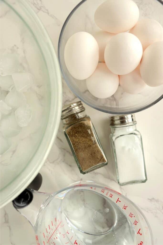 Overhead shot of eggs, water, and ice in bowls next to salt and pepper shakers.