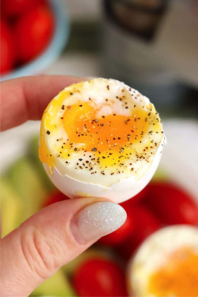 Closeup shot of hand holding half of a soft boiled egg.