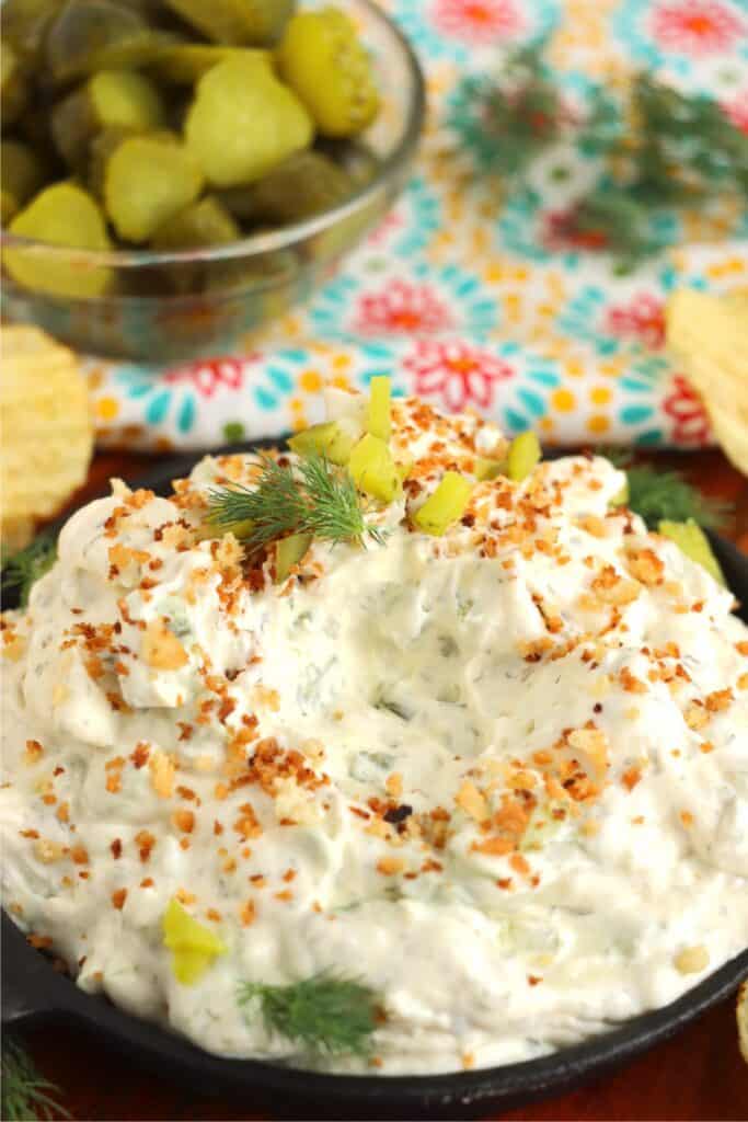 Closeup shot of bowlful of fried dill pickle and ranch dip with scoop removed. 