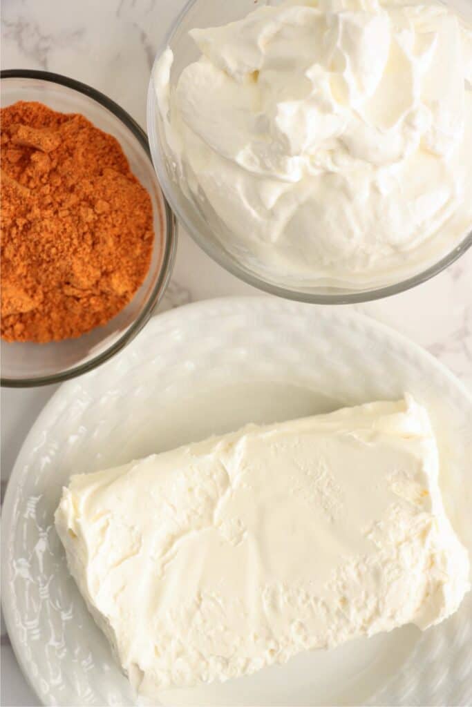 Closeup overhead shot of plateful of cream cheese and bowls of sour cream and taco seasoning. 
