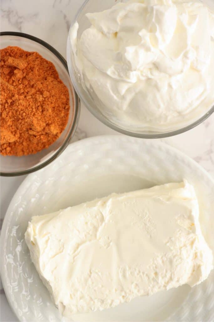 Closeup overhead shot of plateful of cream cheese and bowls of sour cream and taco seasoning. 