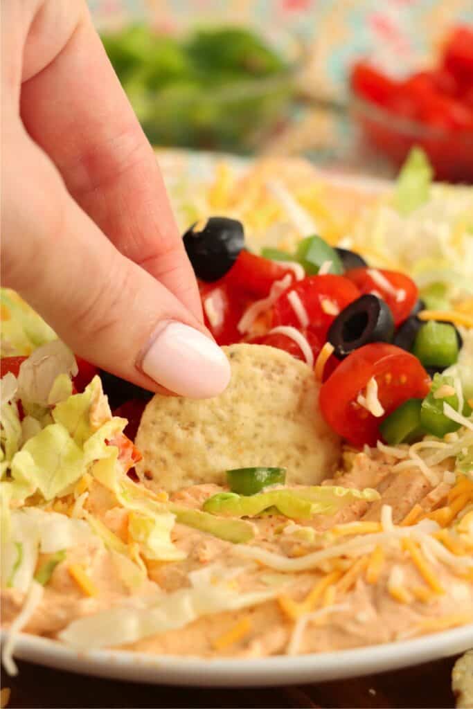 Closeup shot of tortilla chip being dipped into 3 ingredient taco dip. 