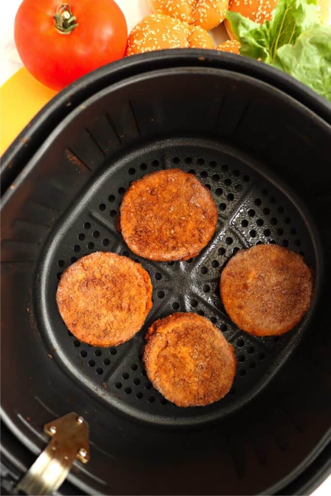 Overhead shot of frozen chicken patties in air fryer basket. 