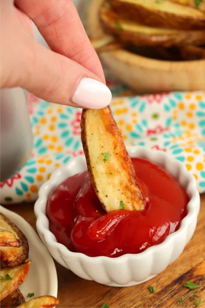 Closeup shot of air fryer steak fry being dipped into a bowl of ketchup.