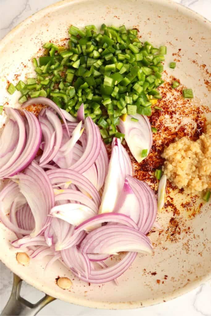 Overhead shot of onions, garlic, and jalapenos in skillet. 