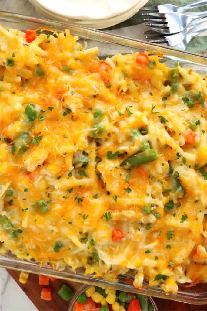 Closeup overhead shot of casserole dish full of cheesy, baked chicken hash brown casserole. 