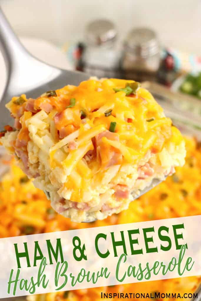 Closeup shot of slice of ham and cheese hash brown casserole on spatula over baking dish with more casserole.
