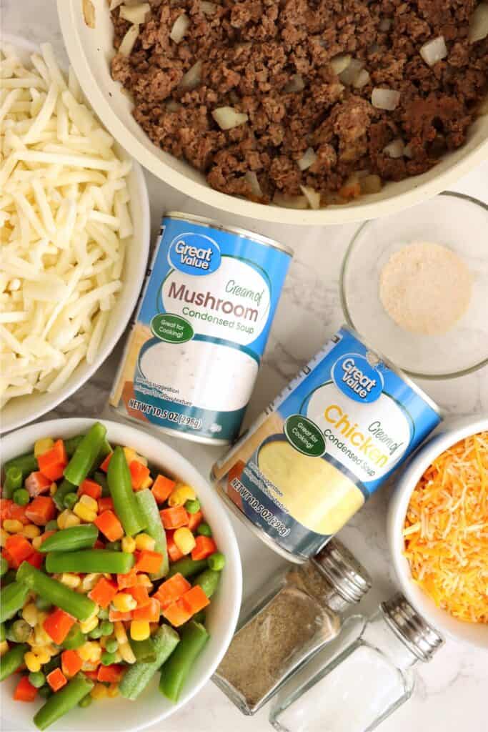 Overhead shot of individual ground beef and hash brown casserole ingredients in bowls on table