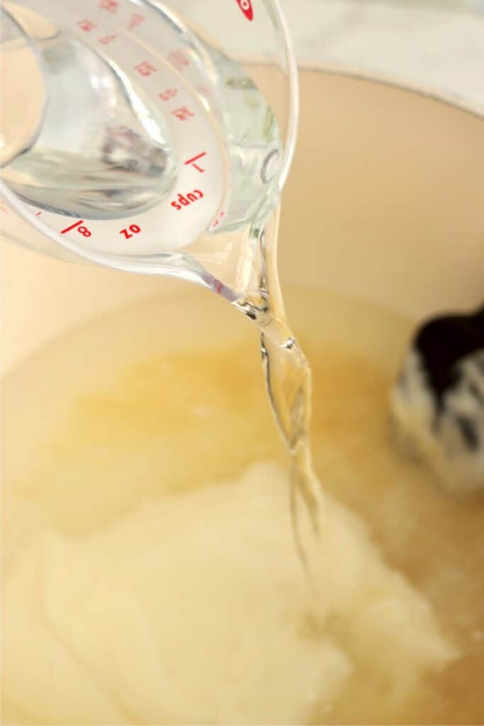 Water being poured into a potful of other cucumber ingredients. 