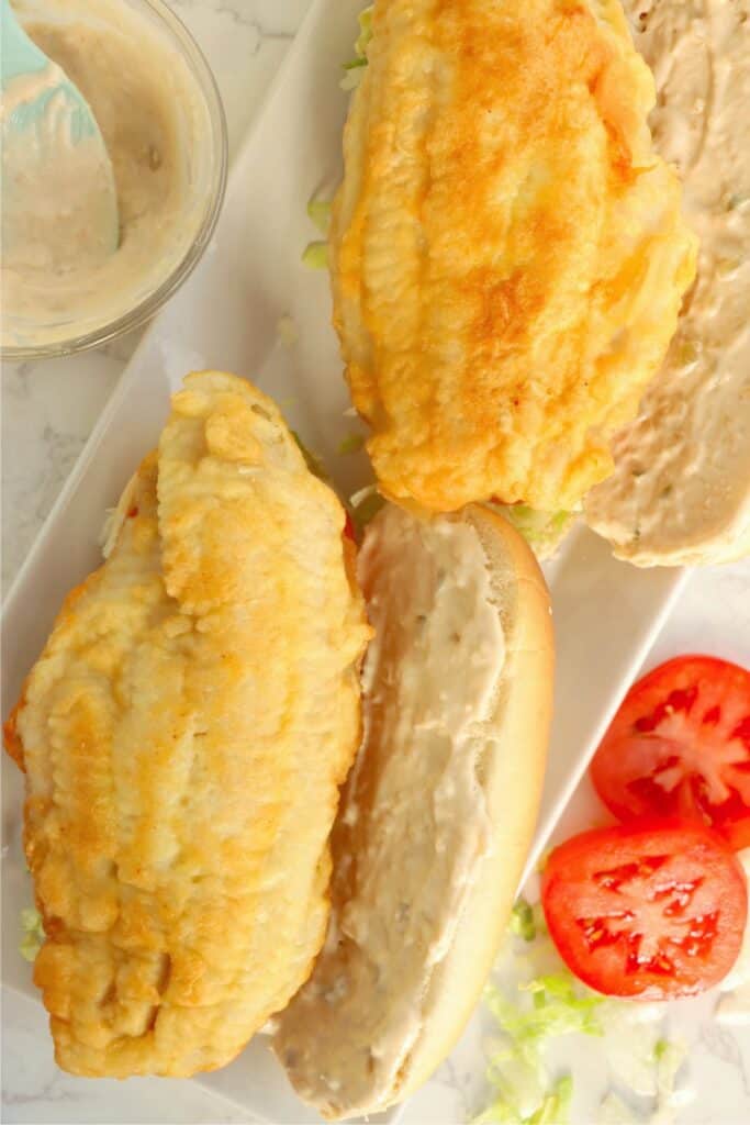 Closeup overhead shot of open-faced catfish po boys on plate. 