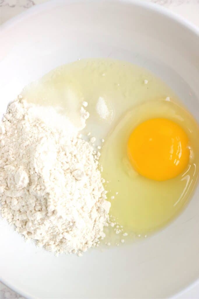 Closeup overhead shot of egg, flour, salt, and sugar in bowl