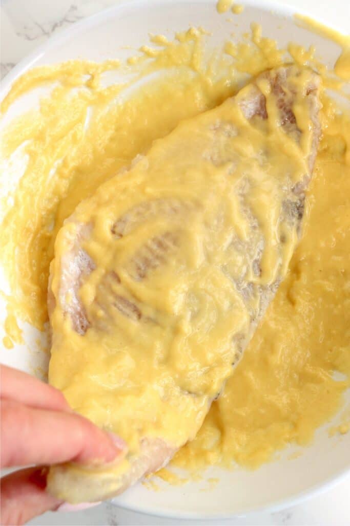 Closeup overhead shot of catfish filet being dredged in coating. 