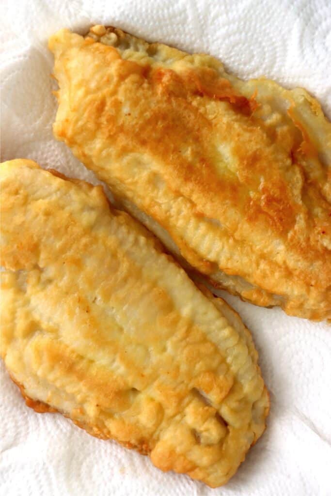 Closeup overhead shot of breaded fried catfish filets on plate lined with paper towels