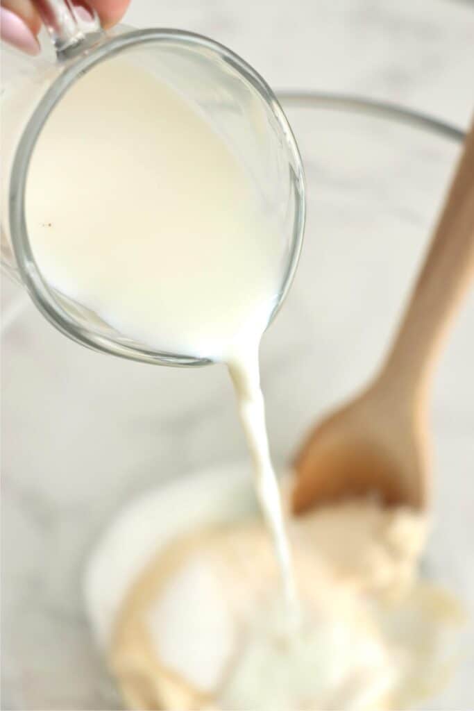 Milk being poured into mixing bowl with coleslaw ingredients.