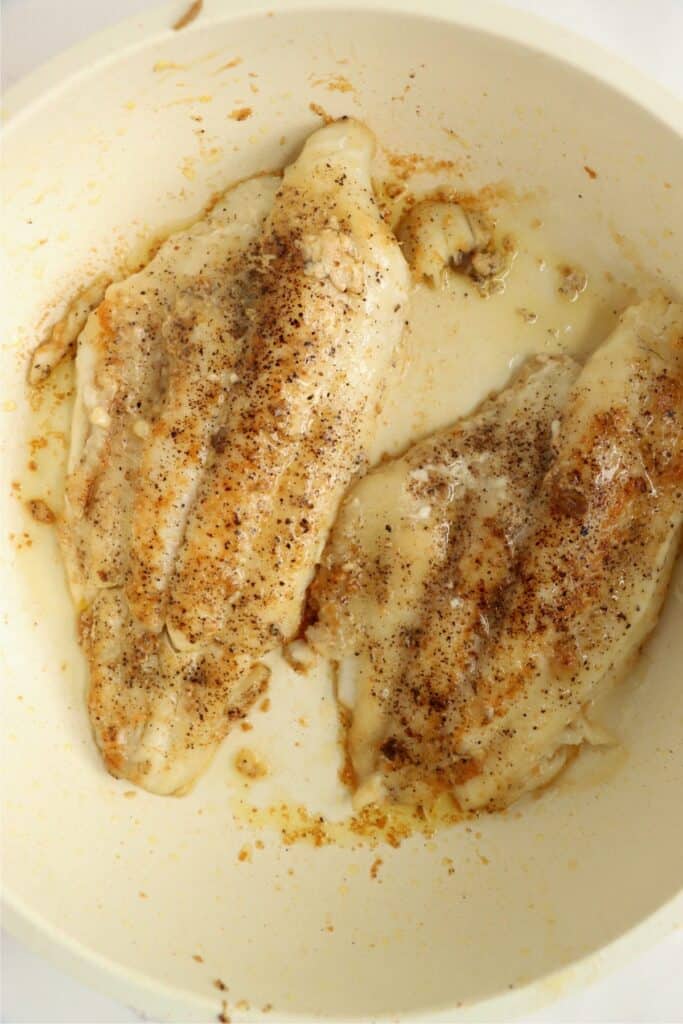 Overhead shot of golden brown catfish filets in skillet. 