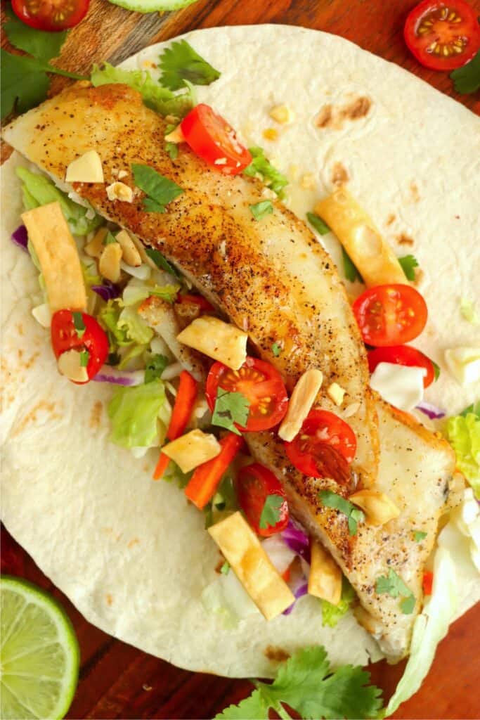 Overhead shot of catfish taco with Asian salad, nuts, and wonton strips.