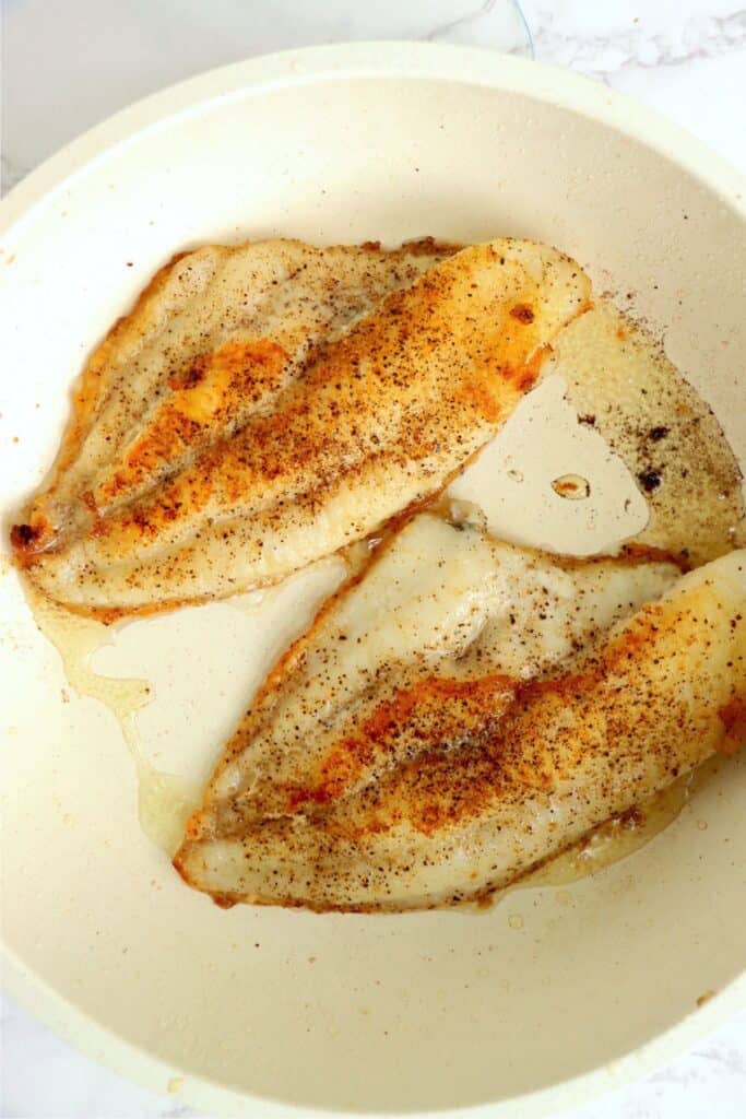 Overhead shot of golden brown catfish filets in skillet.