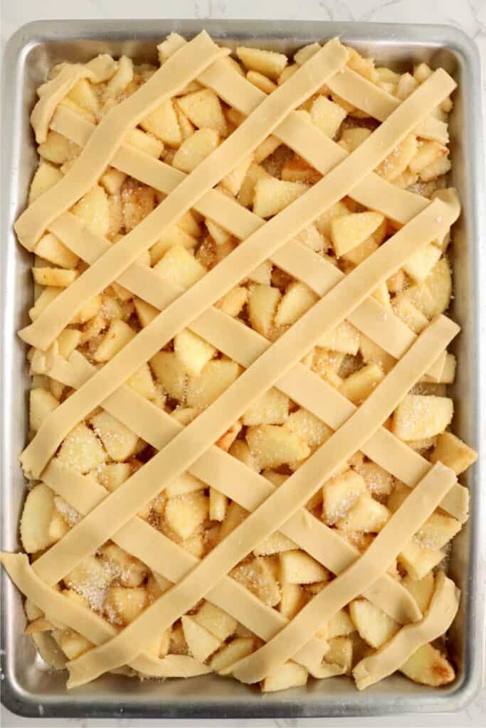 Overhead shot of dough in lattice pattern on top of apple filling.