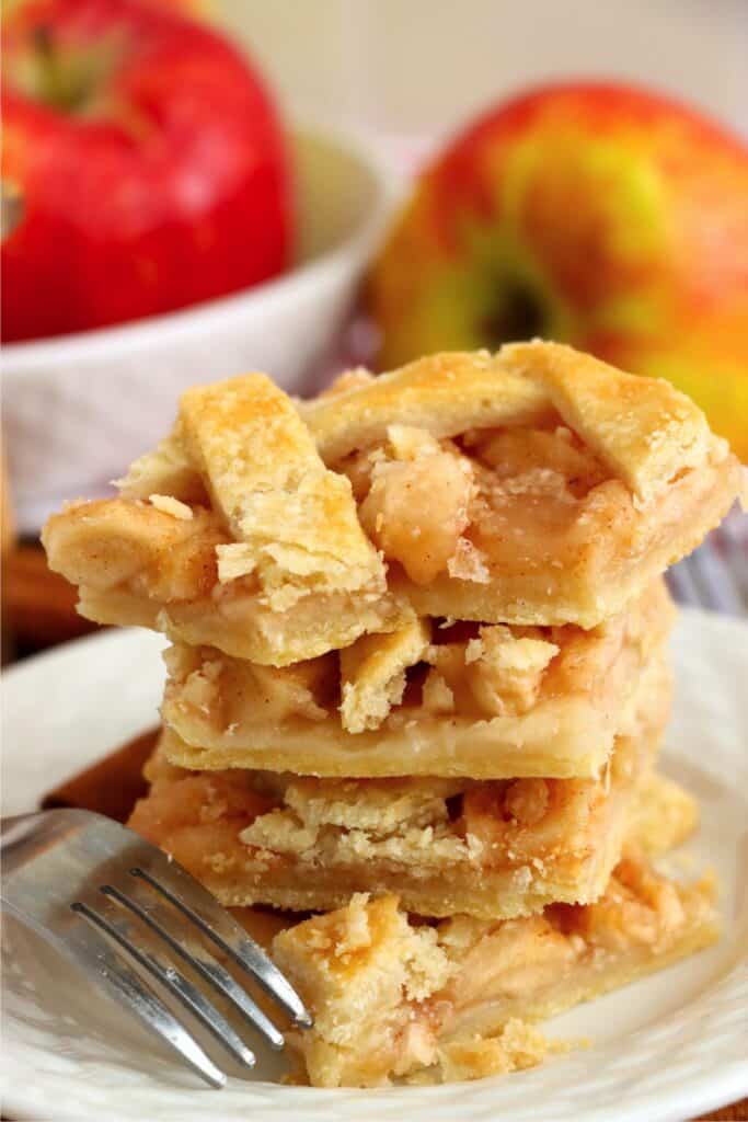 Four homemade apple bars stacked atop one another on plate. 