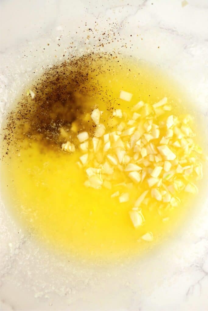 Overhead shot of bowl with melted butter, garlic, salt, and pepper. 