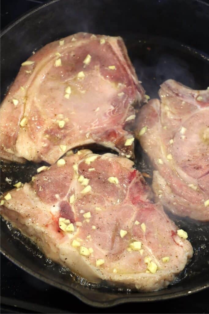 Closeup shot of garlic butter-coated pork chops in skillet. 