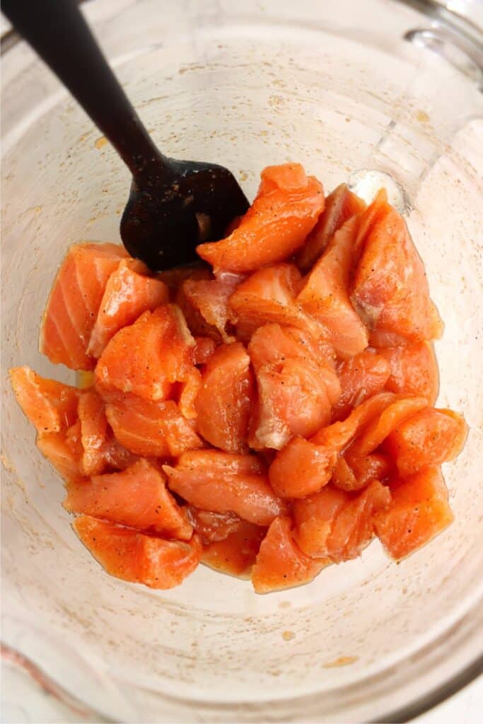 Overhead shot of salmon chunks mixed with seasoning. 