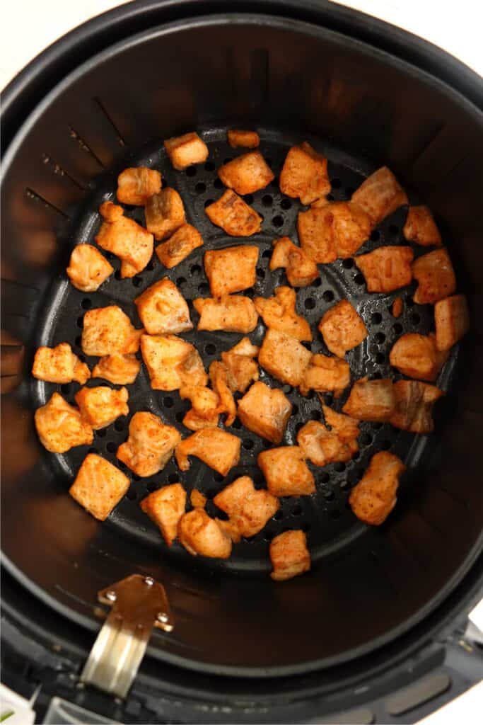 Overhead shot of golden brown air fried salmon bites in air fryer basket.