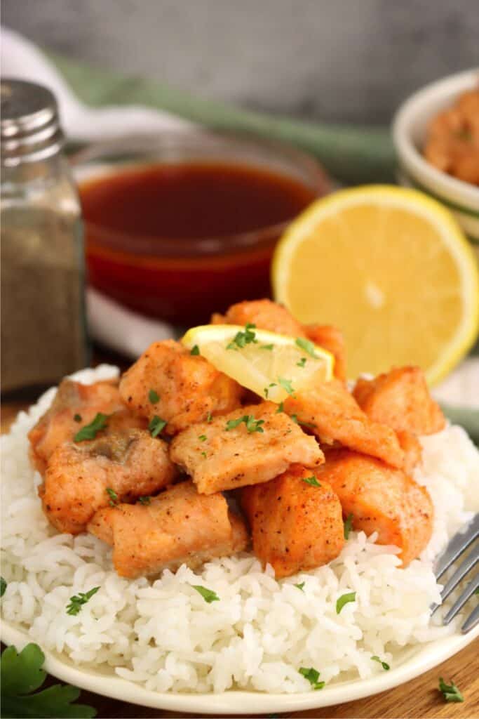 Closeup shot of plateful of white rice topped with air fryer salmon bites. 