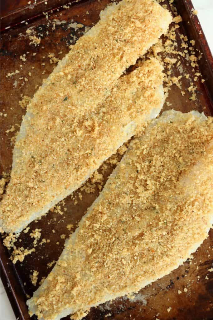 Overhead shot of uncooked breaded cod on baking sheet. 