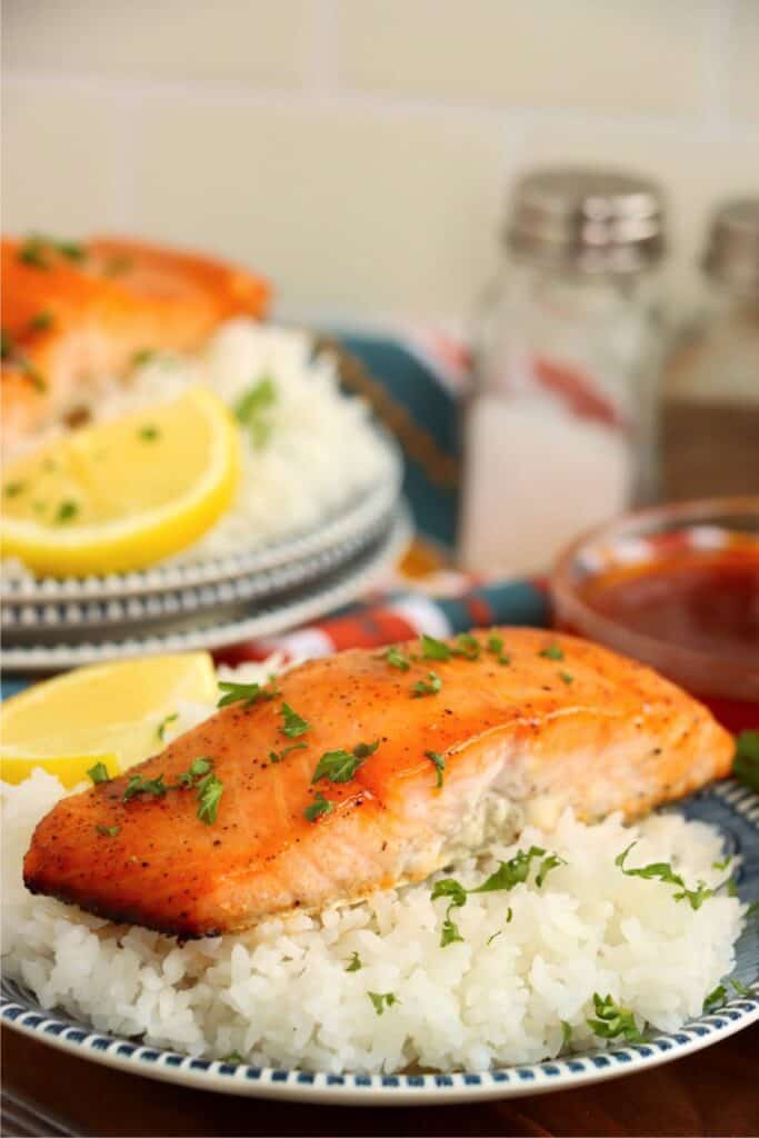 Closeup shot of plateful of white rice topped with a hot honey salmon fillet. 