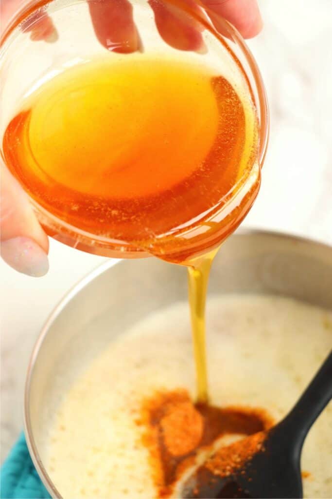 Overhead shot of honey being poured into saucepan with other sauce ingredients. 