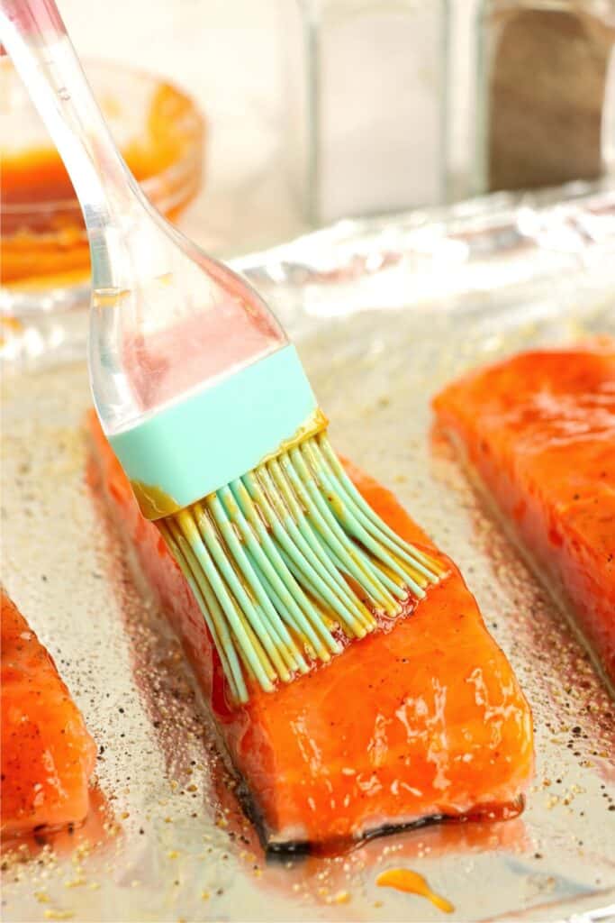 Closeup shot of hot honey sauce being brushed on salmon. 