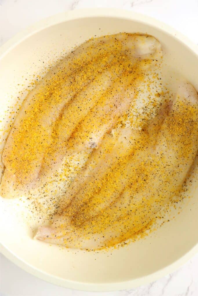 Overhead shot of seasoned catfish filets in skillet.